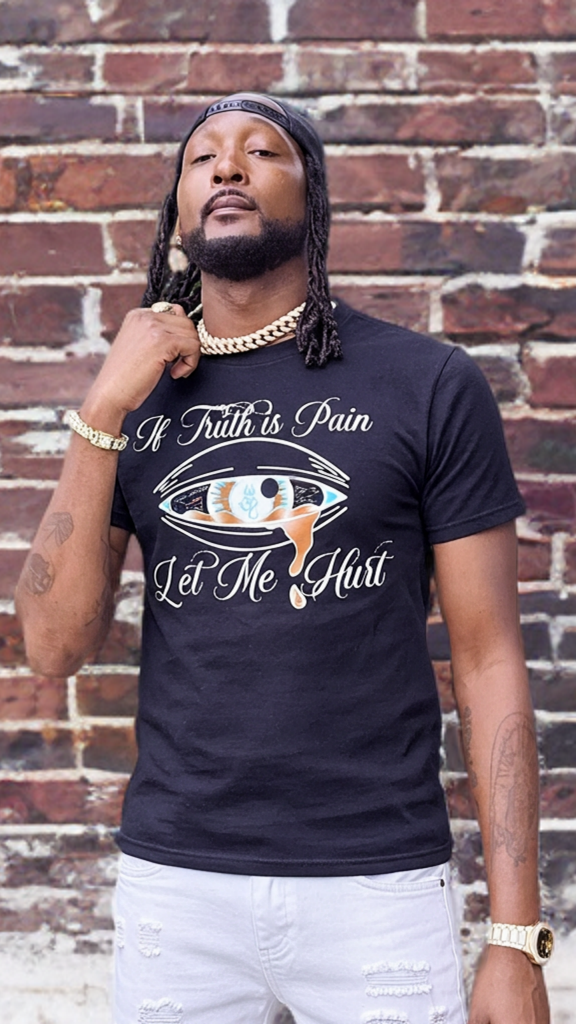 Man wearing a black t-shirt with text and graphics against a brick wall.