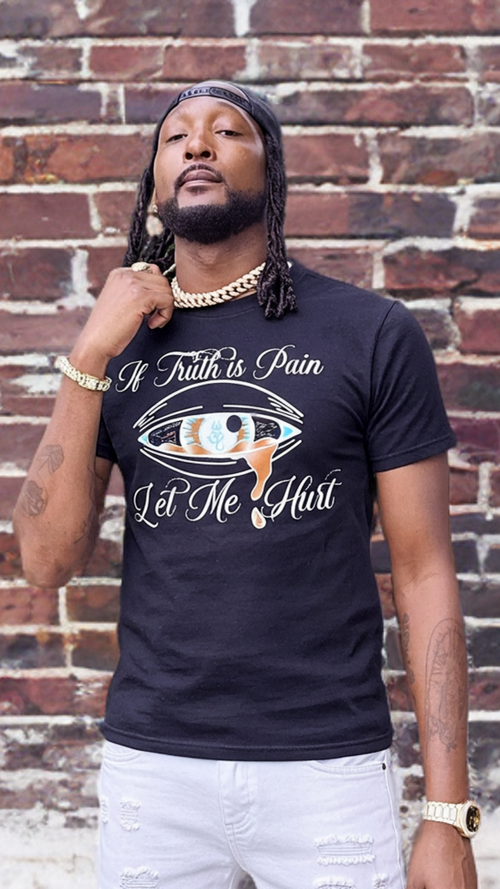 Man wearing a black t-shirt with text and graphics against a brick wall.