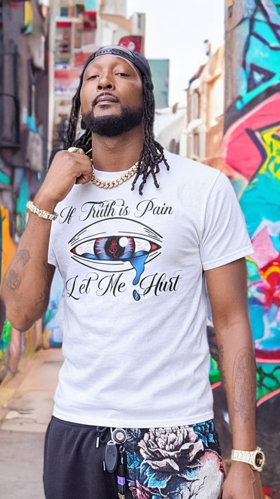 Man wearing a white t-shirt with graphic design and text, standing in an alley with colorful graffiti.