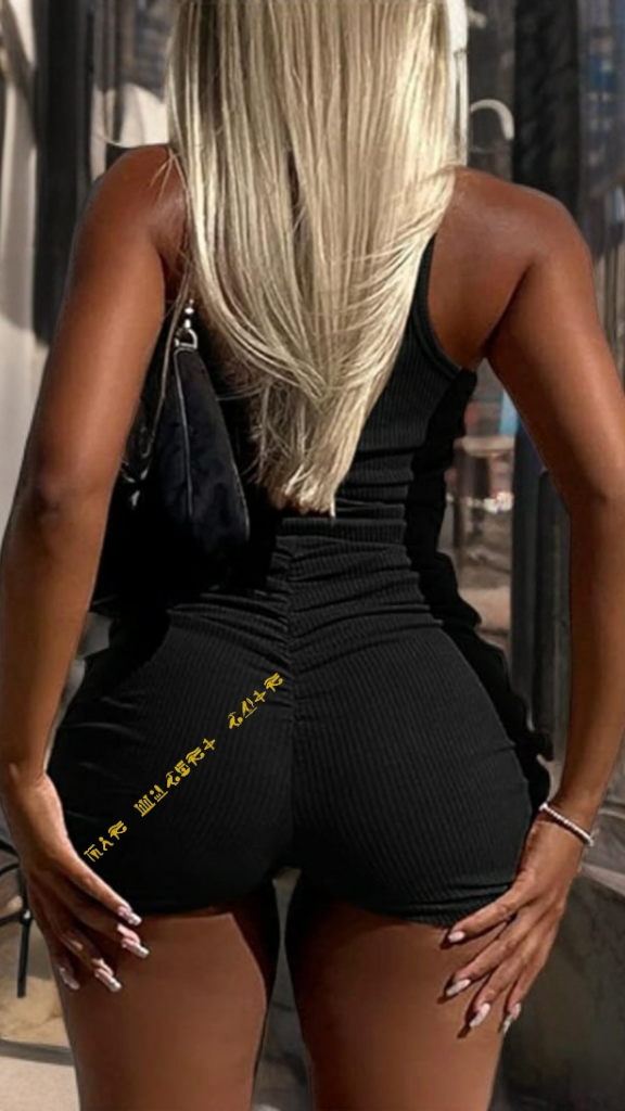 Person wearing a black outfit with yellow text in an urban setting