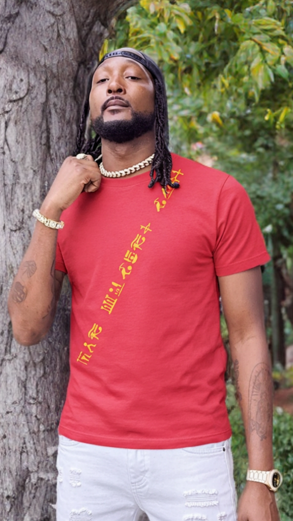 Man wearing a red t-shirt with yellow text, standing outdoors near trees.